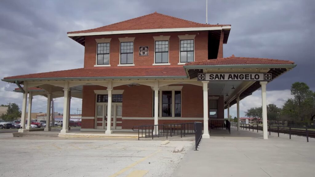 A historic train station with red brick and a welcoming porch